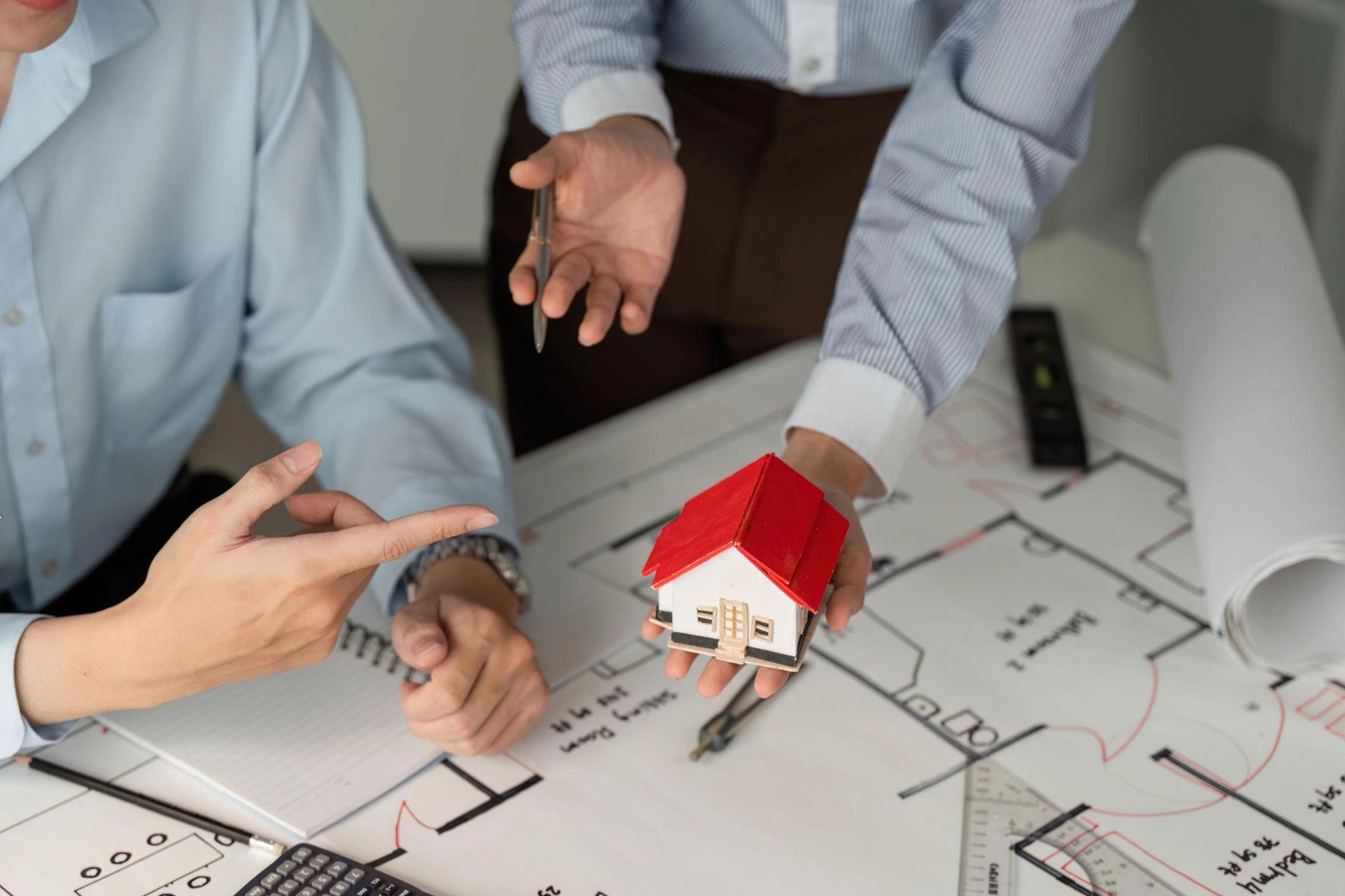 Professionals reviewing a house model and blueprints